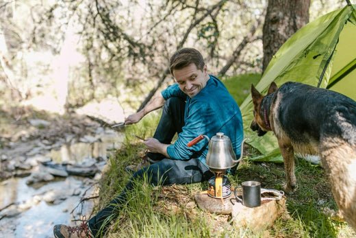 man camping looking at his pet dog