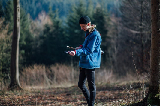 man using a pocket knife on a stick