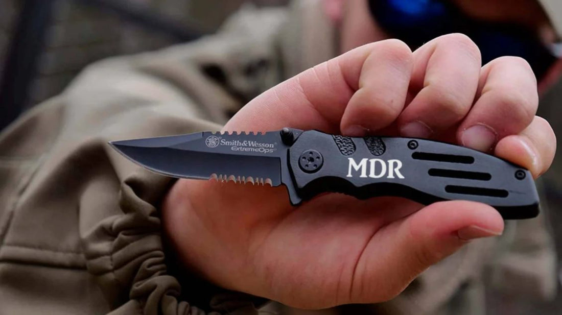 a man holding an engraved black smith and wesson pocket knife