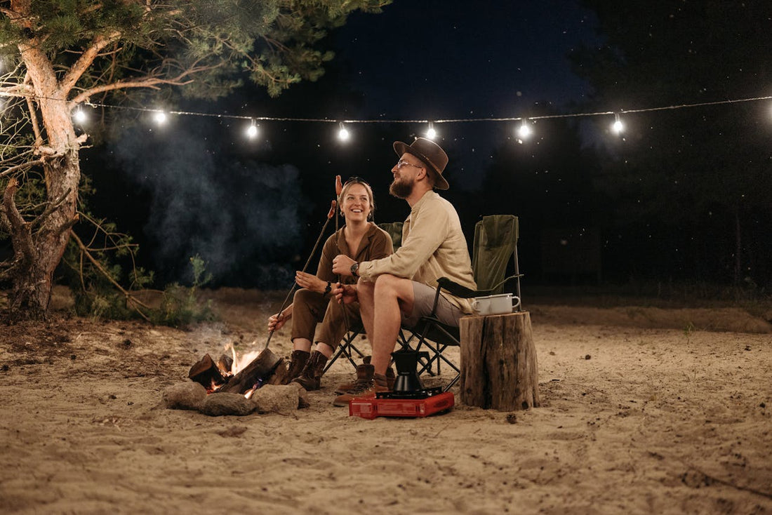 couple sitting on a chair while grilling on campfire