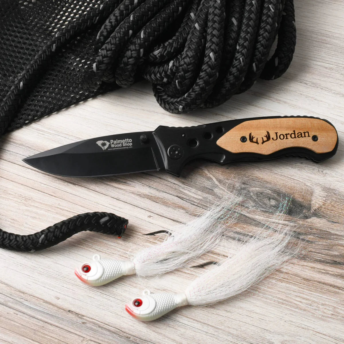 engraved black pocket knife next to fishing lures