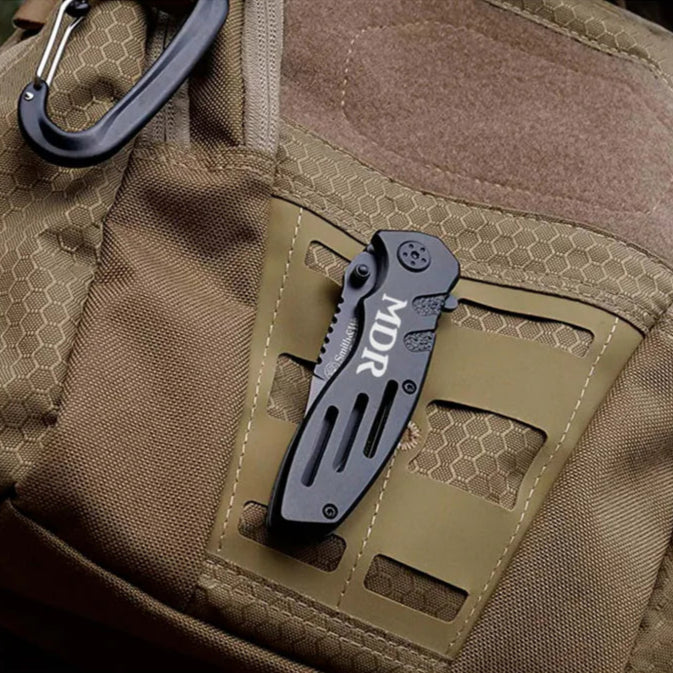 engraved smith and wesson pocket knife sitting on a backpack